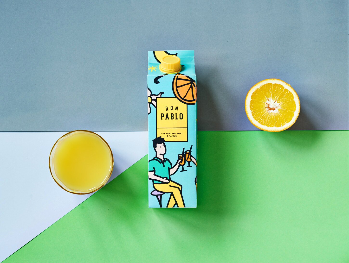 A photography of orange juice carton with glass and a half of orange