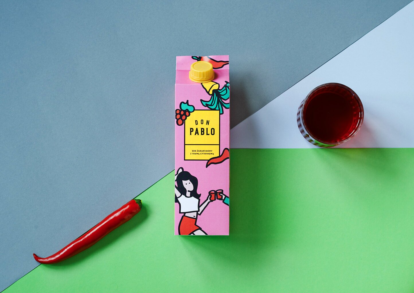 A photography of cranberries juice carton with glass and chilli pepper