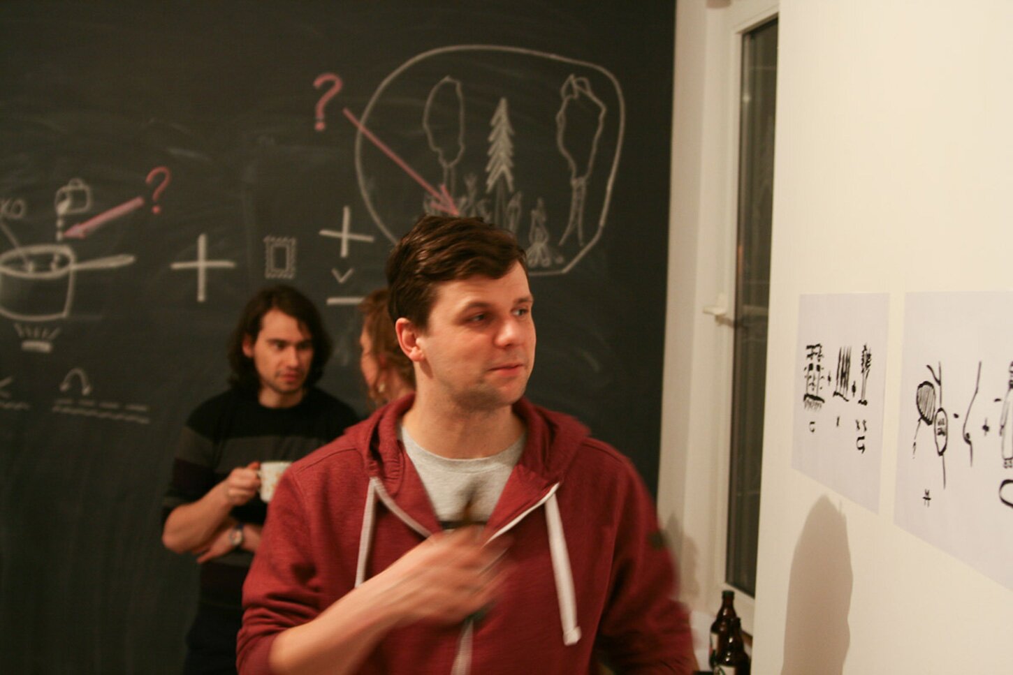A photography of a man looking at a rebus illustration hanging on the wall.